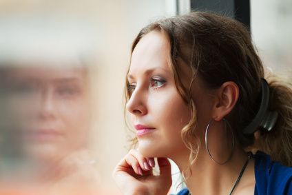 Beautiful young woman with cocktail looking through a restaurant window.